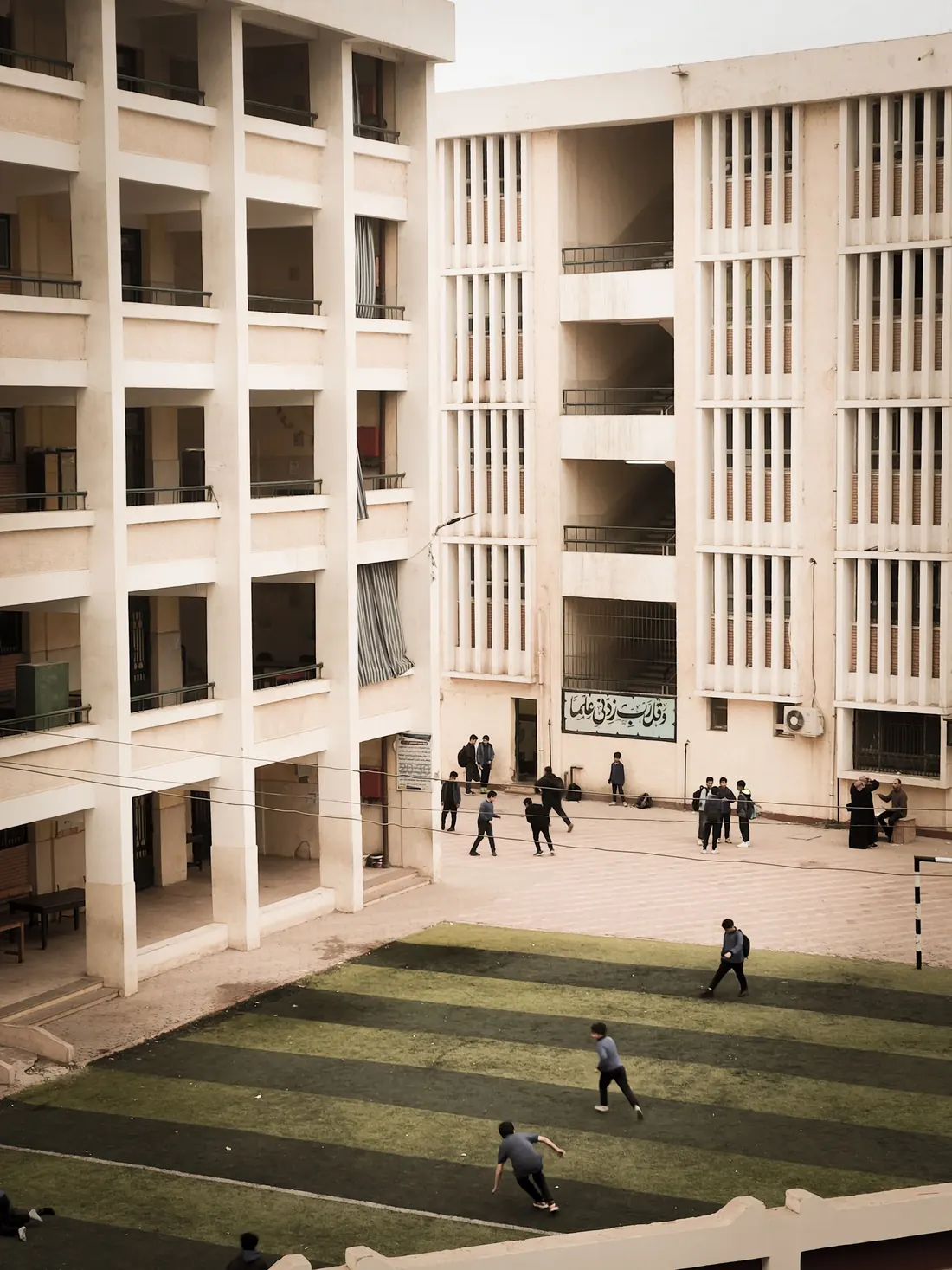 A school campus building overlooking a courtyard where pupils are playing