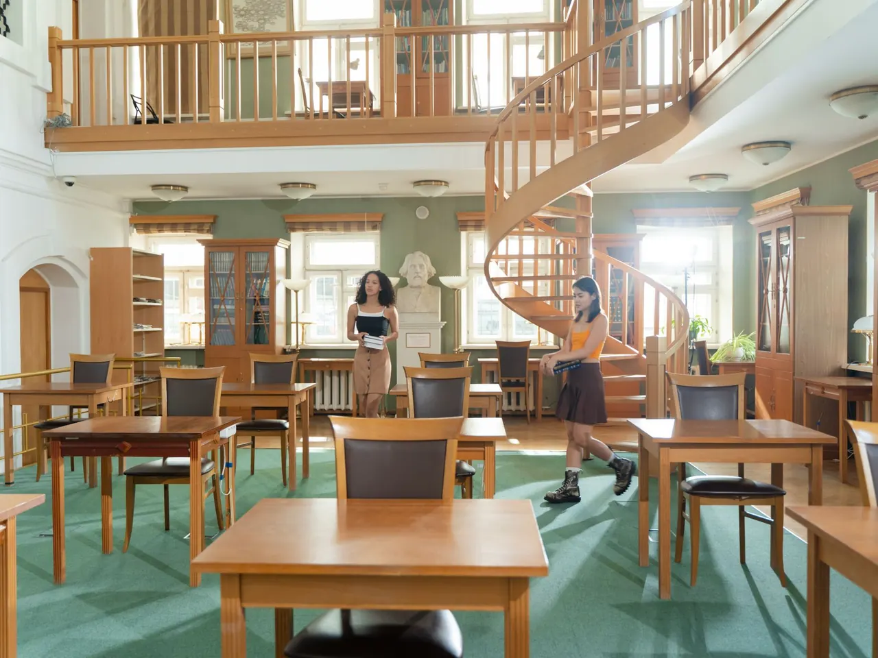 A school library reading room with study tables and full bookshelves