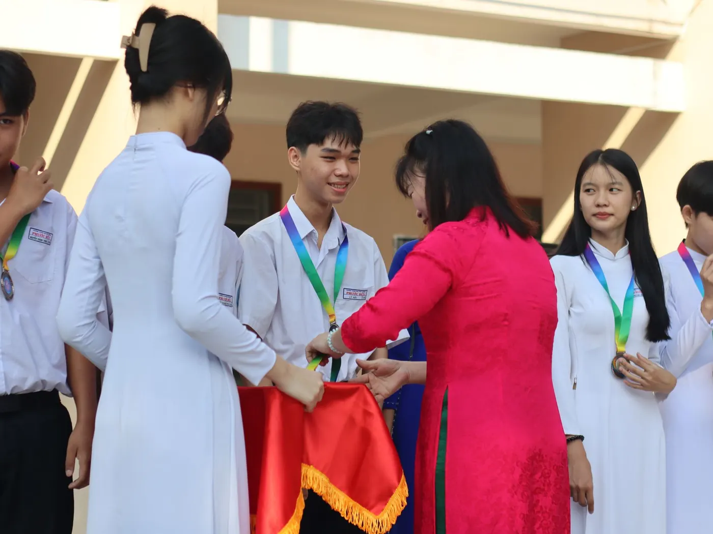 Students in uniform receiving medals and awards from a teacher on prize day