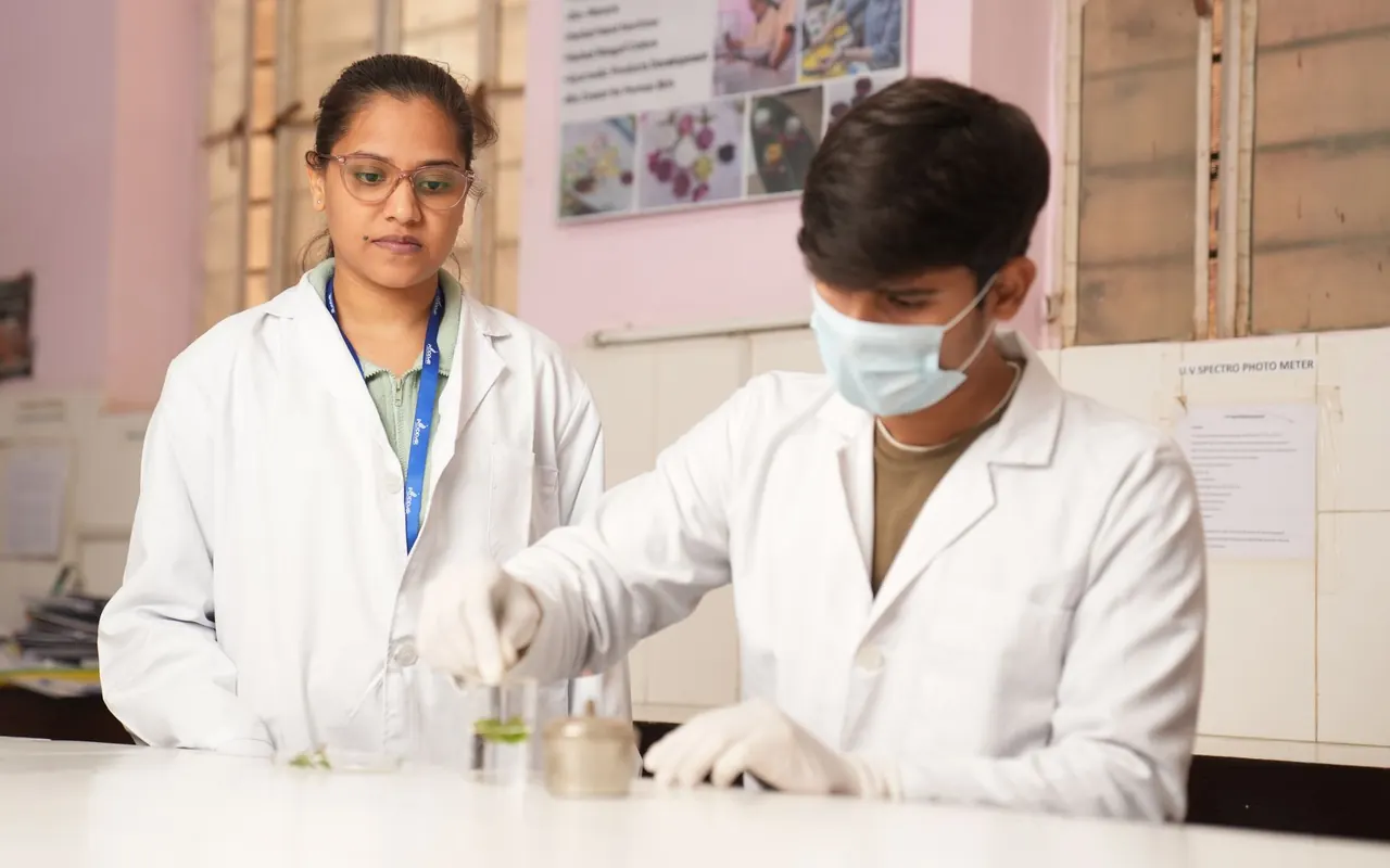 Two students in lab coats running an experiment at a school science bench
